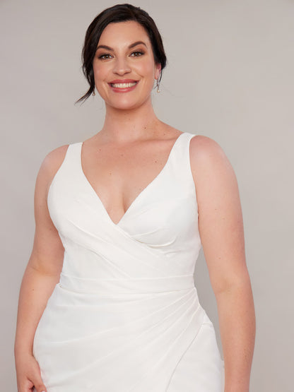 A close-up of a bride wearing an ivory mermaid wedding dress with a V-neckline and ruched detailing.