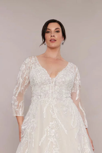 "Long sleeve lace bridal gown with plunging sweetheart neckline, beaded lace details, and full ballgown skirt."