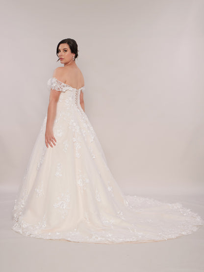 "A bride in a ballgown-style wedding dress with off-the-shoulder lace sleeves and an extended long train